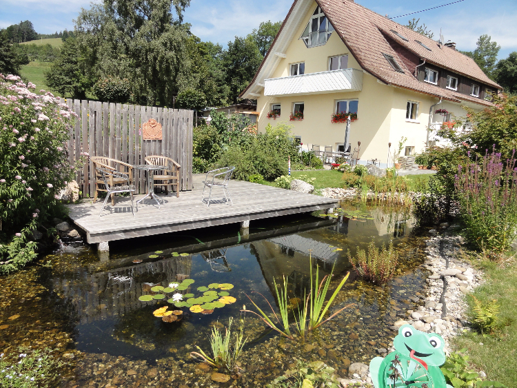 Ein über dem Wasser/Teich schwebendes Holzdeck in St. Peter/ Schwarzwald. Gartenplanung Helmut Lamprecht.