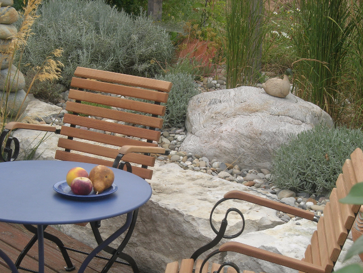Einladendes Gartenbild mit romantischen Gartenmöbeln und gelungener Gestaltung mit Steinen
