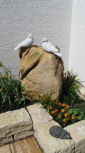 2 weiße Tauben aus Stein sitzt auf einem Naturstein-Findling